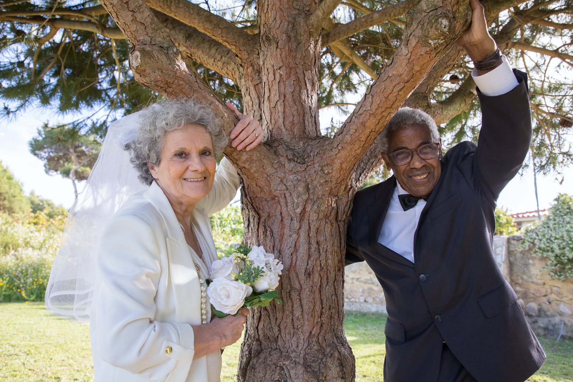 elderly bride and groom standing under the tree
